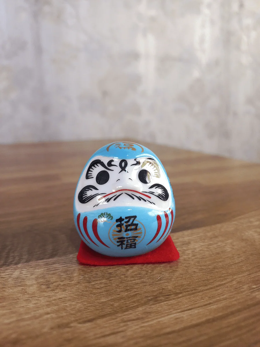Daruma símbolo de motivación y perseverancia para escritorio color celeste