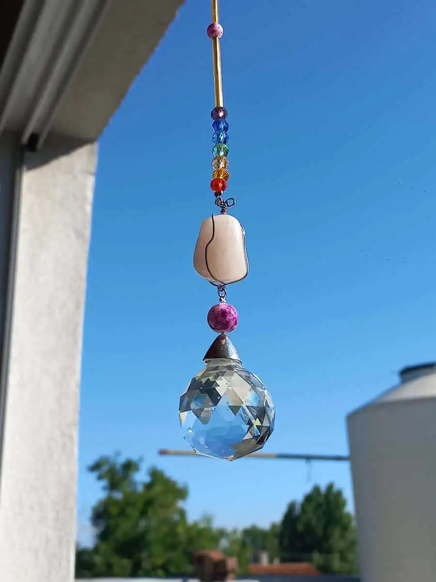 Atrapasol colgante con cuarzo rosa natural y esfera prismática que refleja la luz del sol