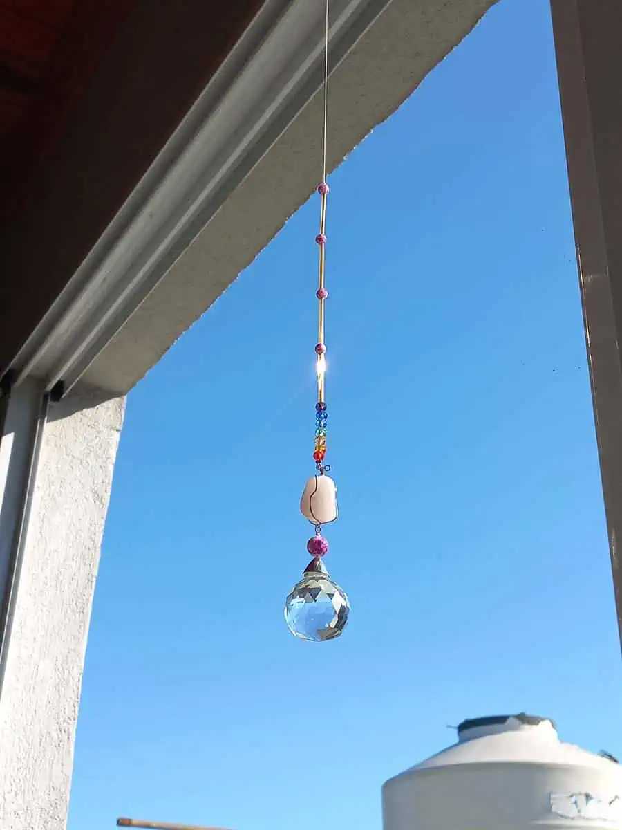 Atrapasol colgante con cuarzo rosa natural y esfera prismática que refleja la luz del sol
