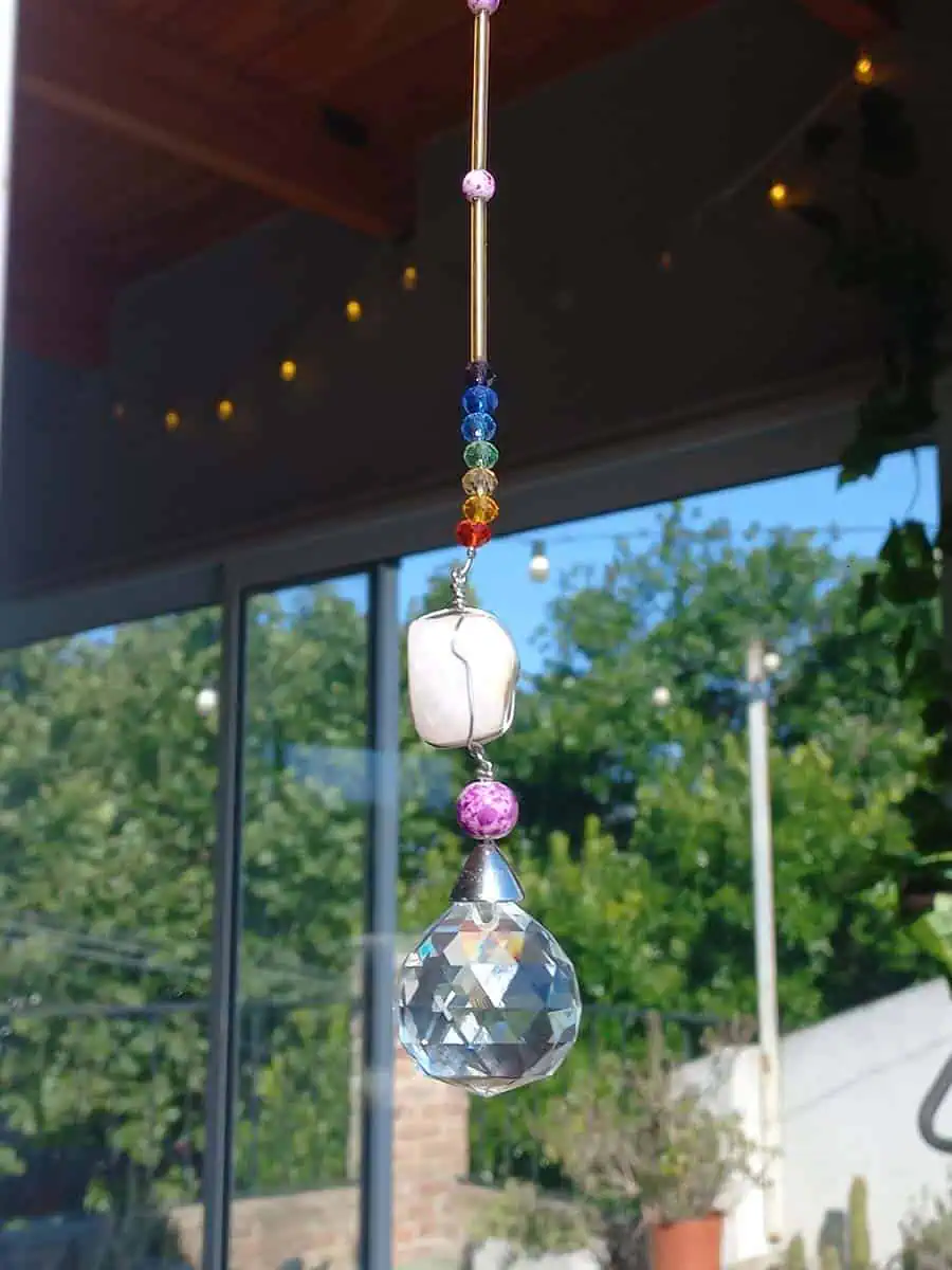Atrapasol colgante con cuarzo rosa natural y esfera prismática que refleja la luz del sol