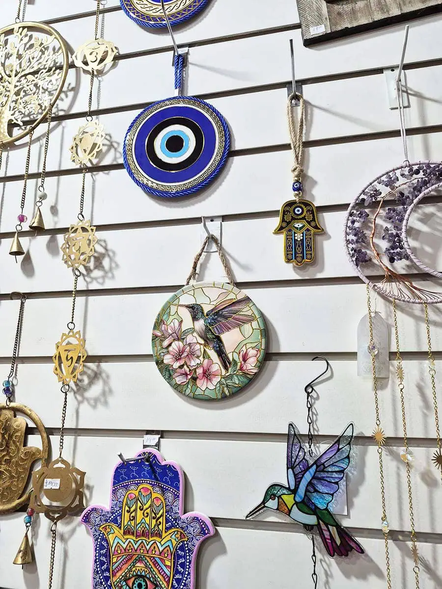 Colgante decorativo de pared de cerámica con un colibrí rodeado de flores rosadas y violetas