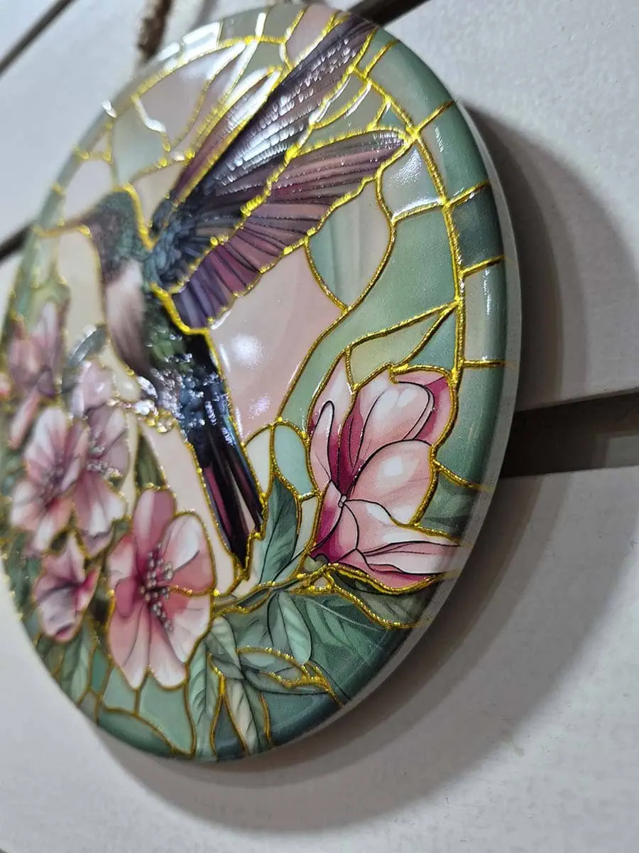 Colgante decorativo de pared de cerámica con un colibrí rodeado de flores rosadas y violetas