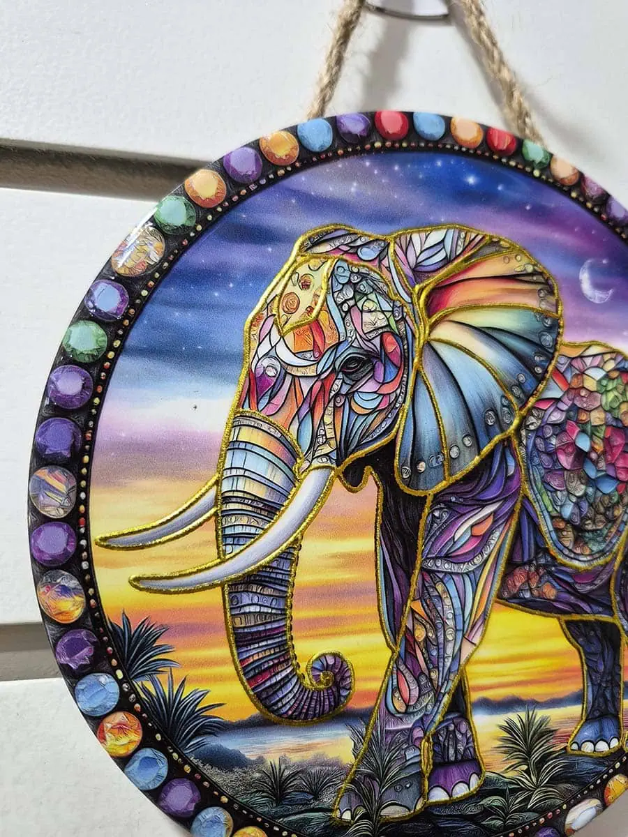 Colgante de pared redondo de cerámica con elefante colorido sobre un paisaje de anochecer