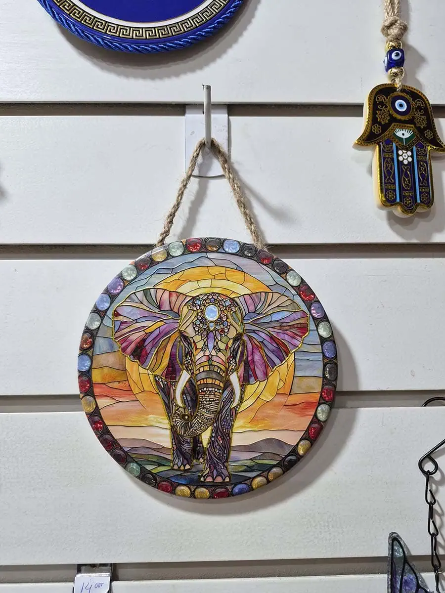 Colgante decorativo de pared de cerámica con un elefante sobre un paisaje de amanecer en tonos cálidos