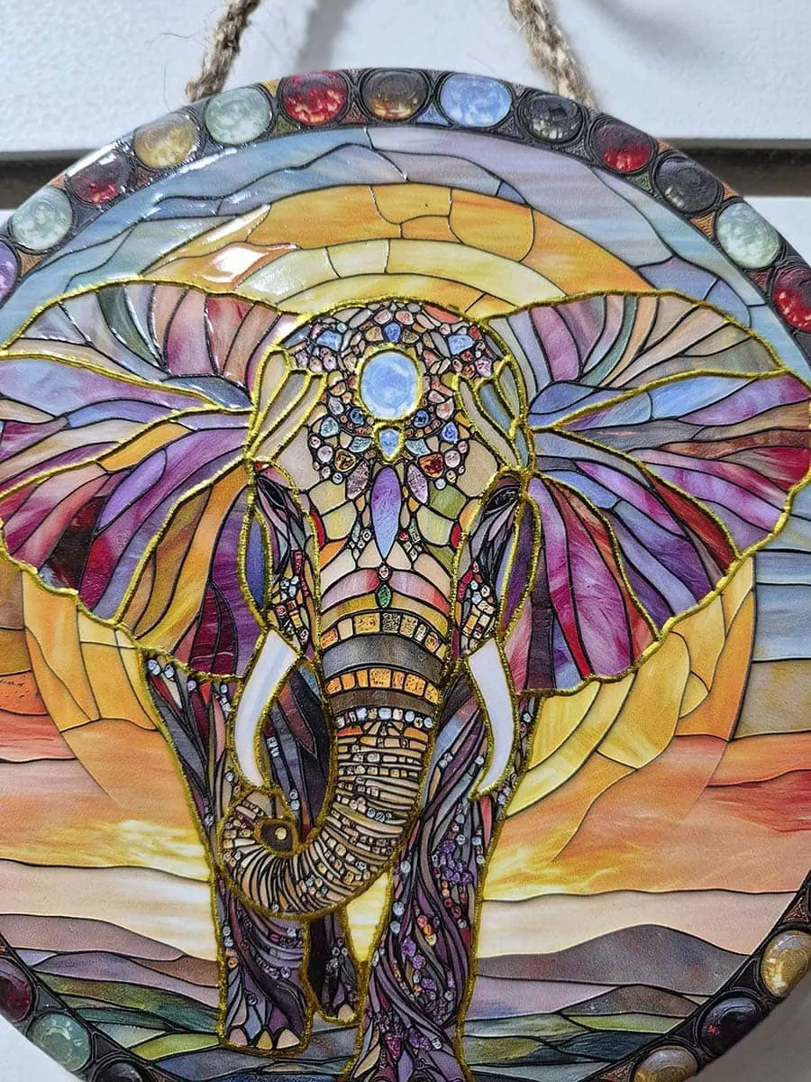 Colgante decorativo de pared de cerámica con un elefante sobre un paisaje de amanecer en tonos cálidos