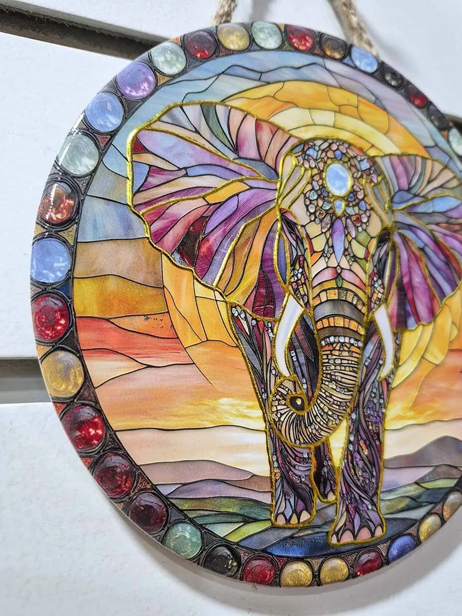 Colgante decorativo de pared de cerámica con un elefante sobre un paisaje de amanecer en tonos cálidos