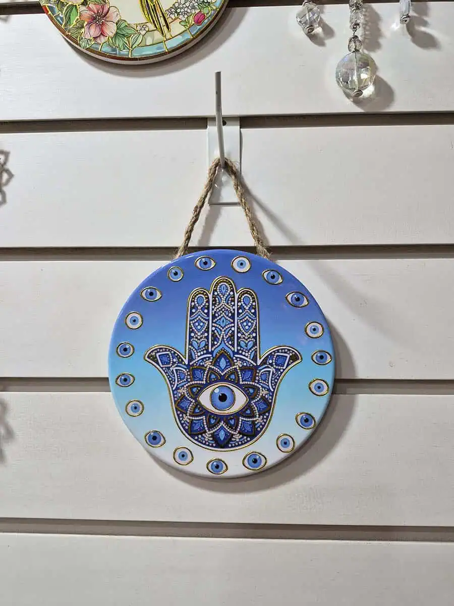 Colgante decorativo redondo de cerámica con Mano de Fátima y ojos turcos sobre fondo celeste