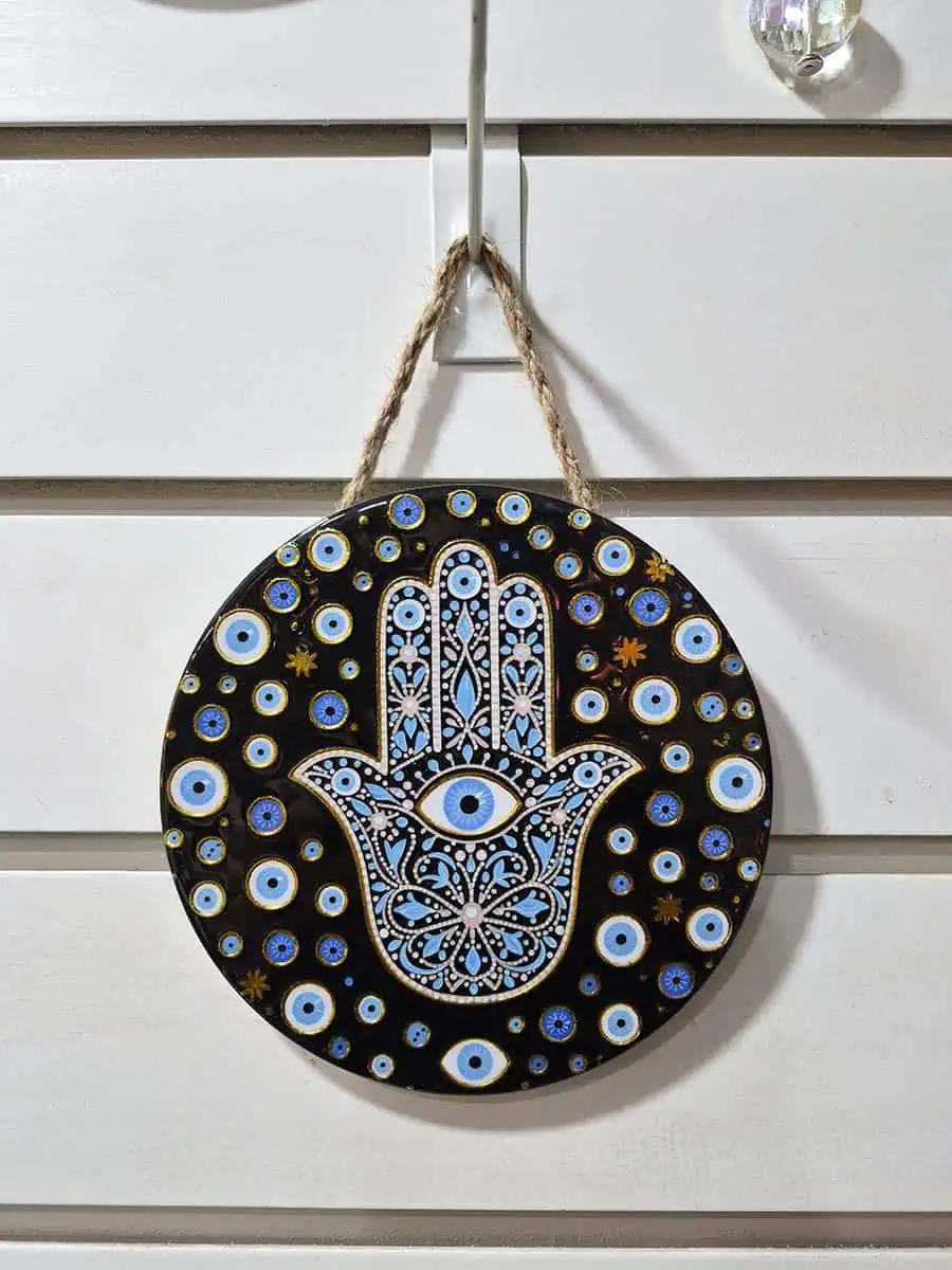 Colgante decorativo redondo de cerámica con Mano de Fátima y múltiples ojos turcos sobre fondo negro