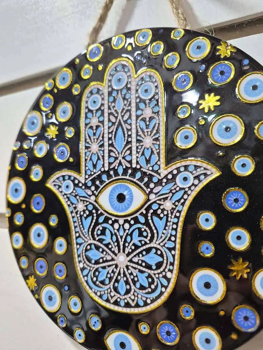 Colgante decorativo redondo de cerámica con Mano de Fátima y múltiples ojos turcos sobre fondo negro