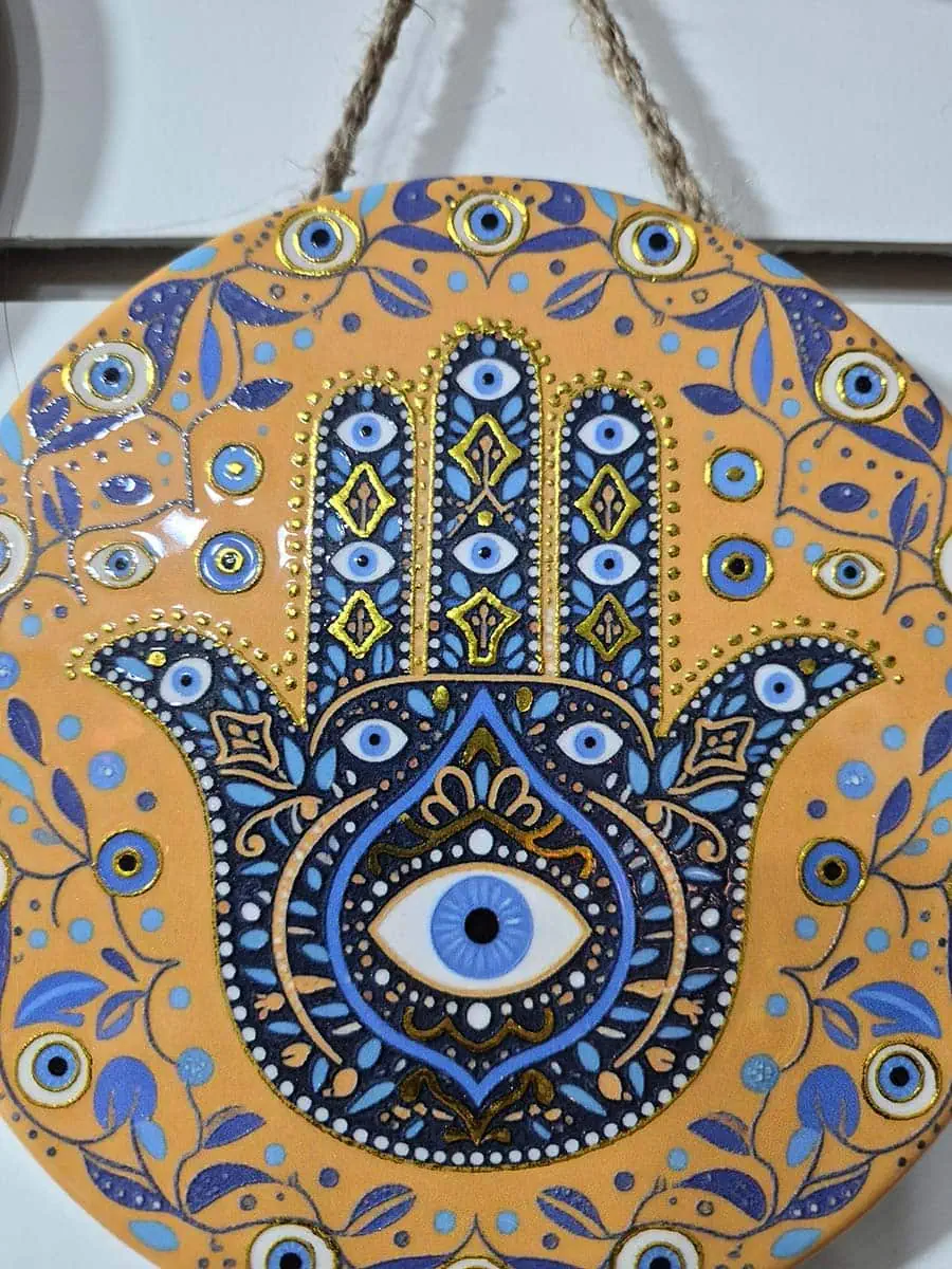 Colgante decorativo redondo de cerámica con Mano de Fátima azul, ojo turco y detalles florales sobre fondo naranja