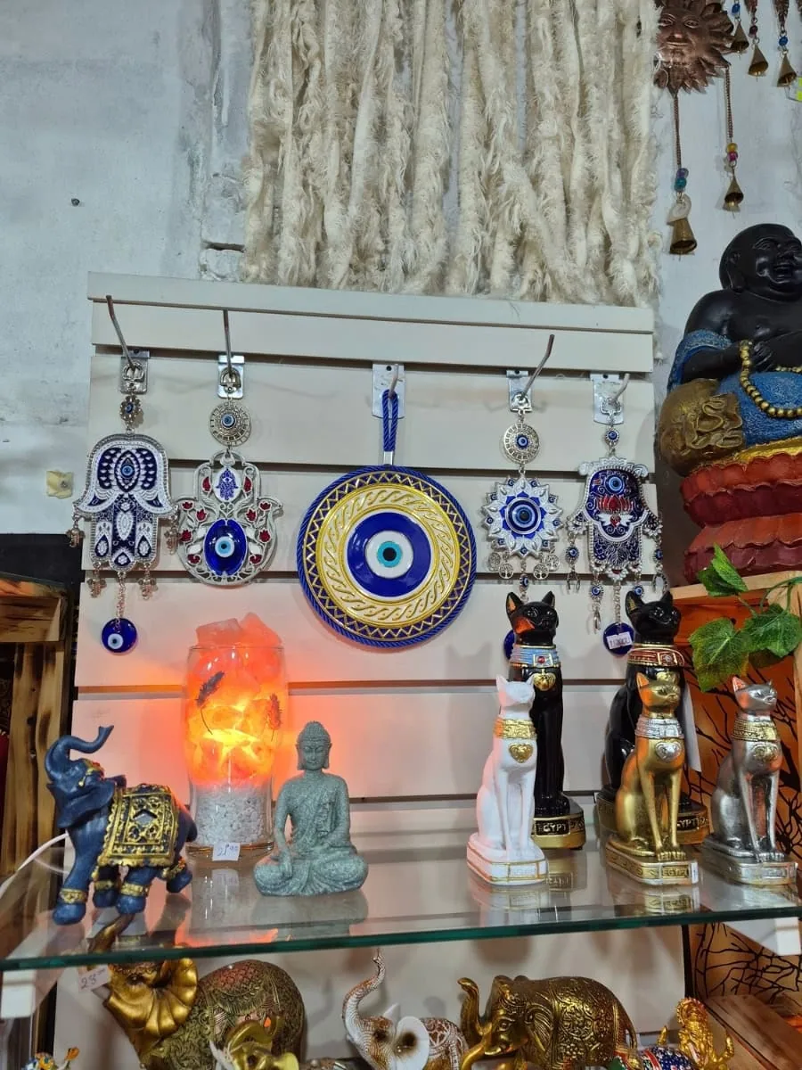 Ojo turco redondo azul con borde de triángulos dorados, dibujos curvos sobre fondo blanco y cordón trenzado azul