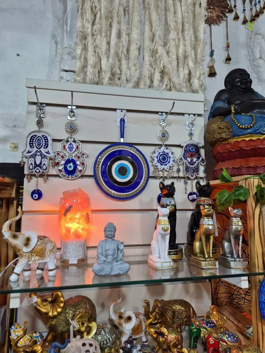 Colgante redondo de ojo turco azul con círculos negros, blancos y celestes, guarda griega dorada y cordón azul para colgar