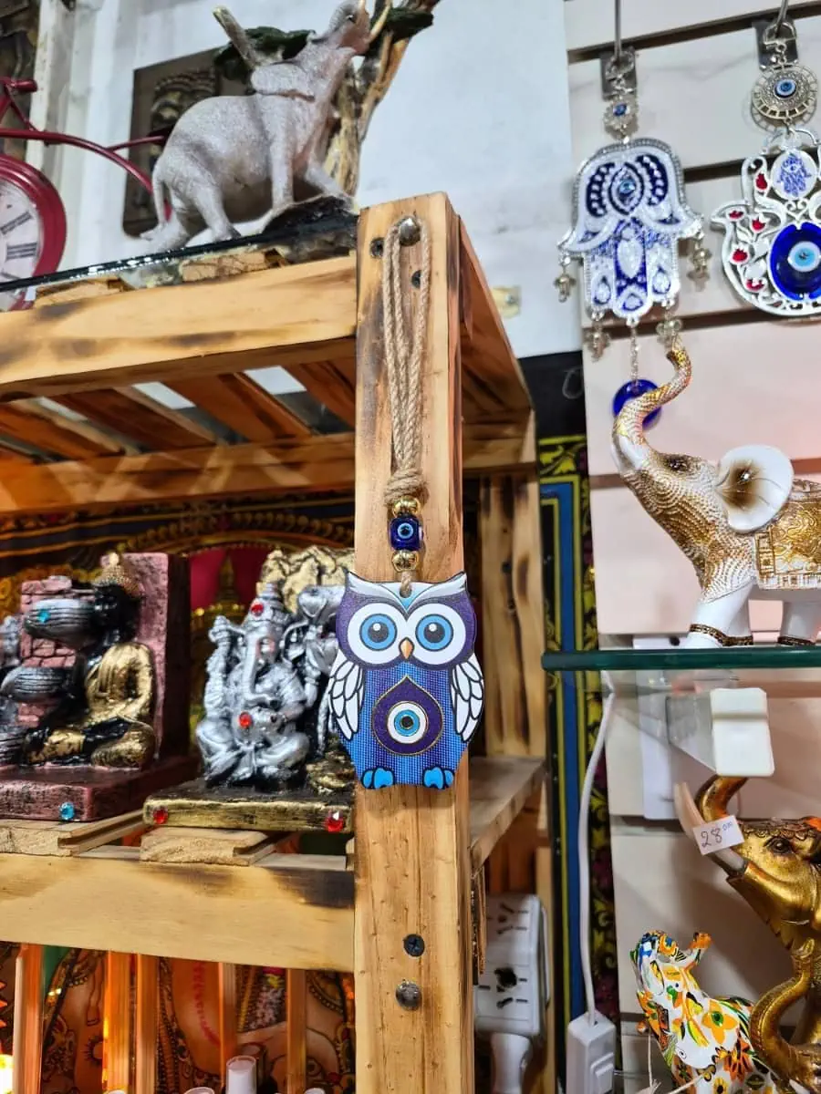 Colgante decorativo de búho violeta con alas blancas, patas celestes y ojo turco azul en el pecho