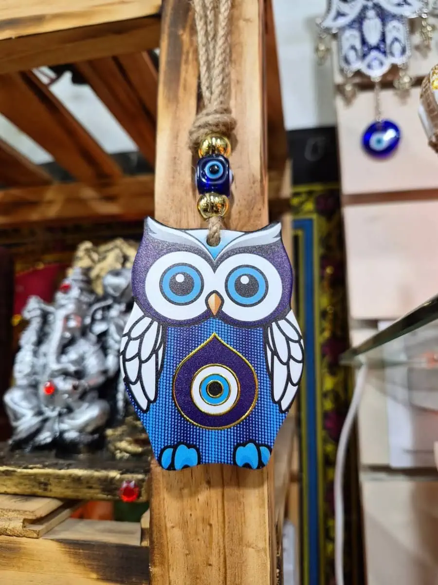 Colgante decorativo de búho violeta con alas blancas, patas celestes y ojo turco azul en el pecho