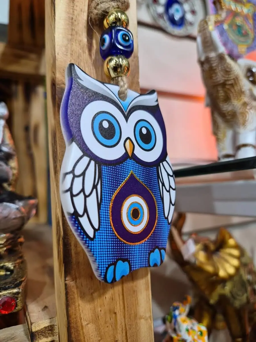 Colgante decorativo de búho violeta con alas blancas, patas celestes y ojo turco azul en el pecho