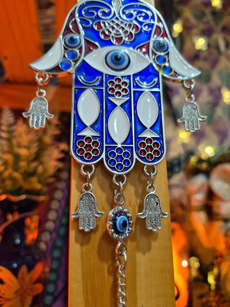 Mano de Fátima azul y blanca con dibujos geométricos, ojo turco central, pequeñas manos colgantes y disco azul inferior