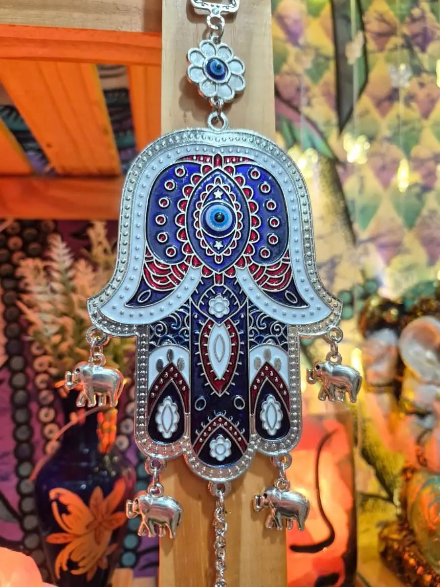 Mano de Fátima azul oscuro con borde plateado, ojo turco central, pequeños elefantes colgantes y disco azul inferior