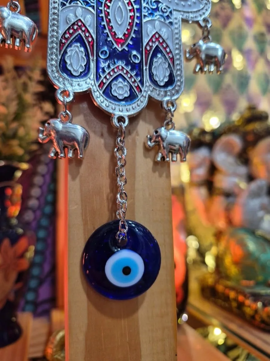 Mano de Fátima azul oscuro con borde plateado, ojo turco central, pequeños elefantes colgantes y disco azul inferior