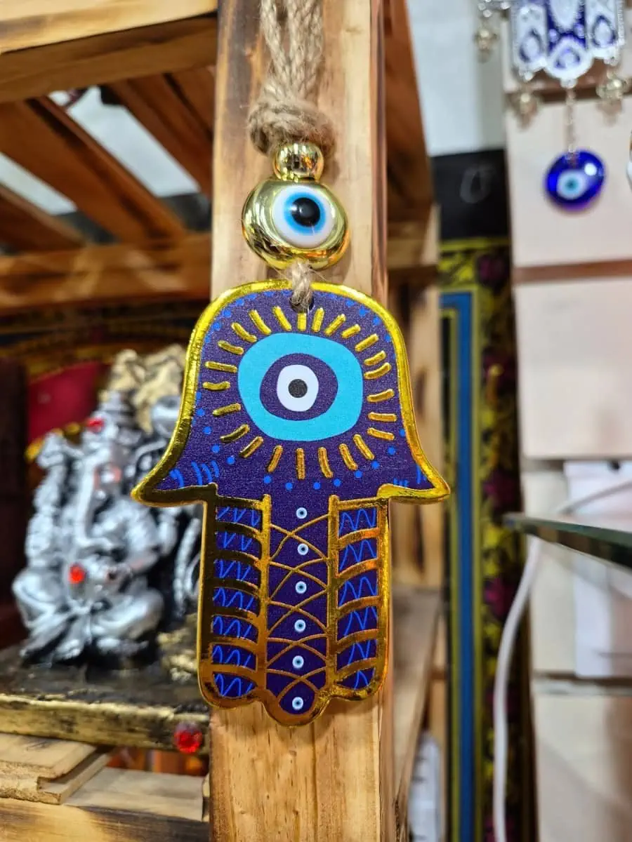 Colgante Mano de Fátima azul intenso con ojo turco blanco y celeste, dibujos dorados y cordón de soga