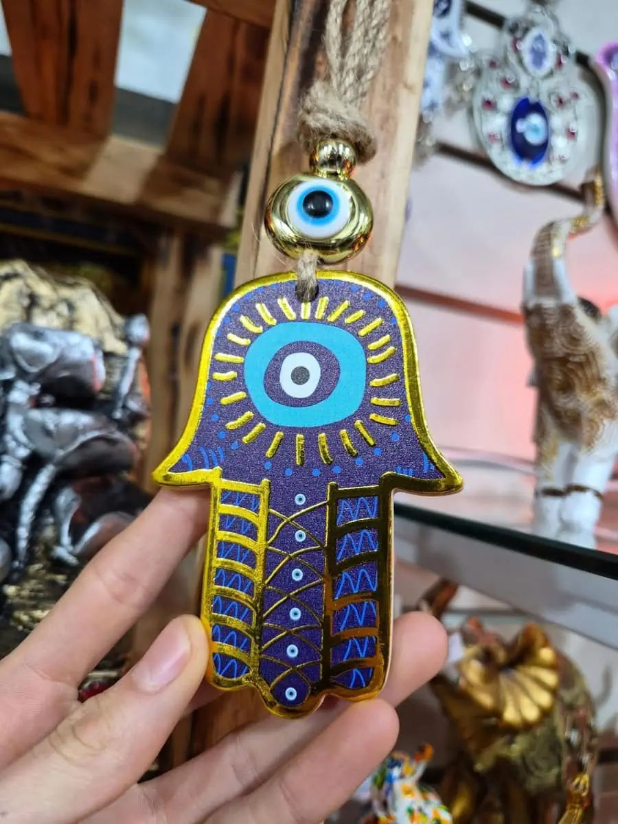 Colgante Mano de Fátima azul intenso con ojo turco blanco y celeste, dibujos dorados y cordón de soga
