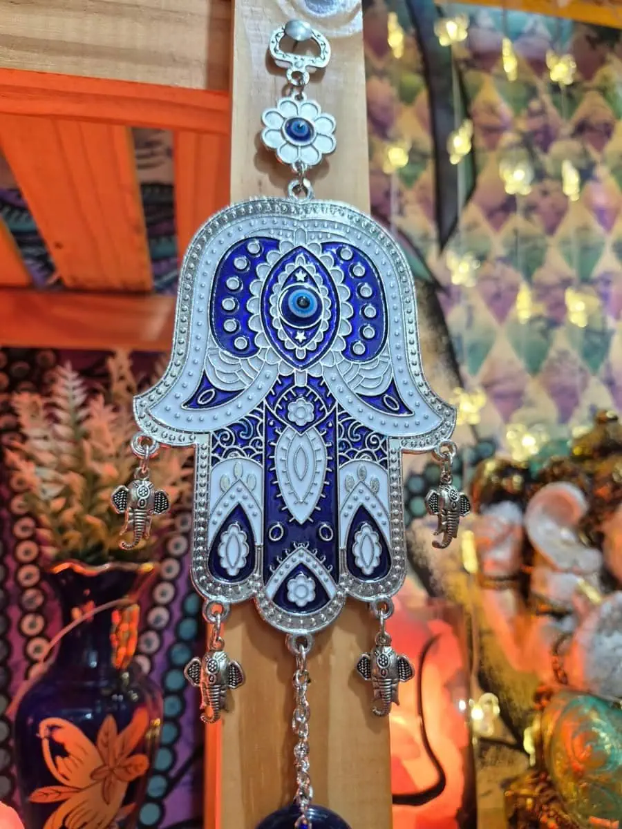 Colgante Mano de Fátima celeste y plateada con dibujos azules, pequeños elefantes laterales y ojo turco inferior