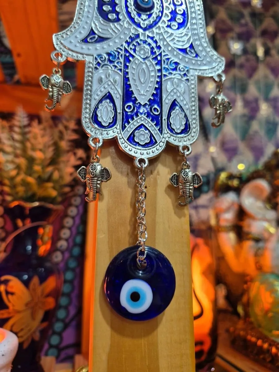 Colgante Mano de Fátima celeste y plateada con dibujos azules, pequeños elefantes laterales y ojo turco inferior
