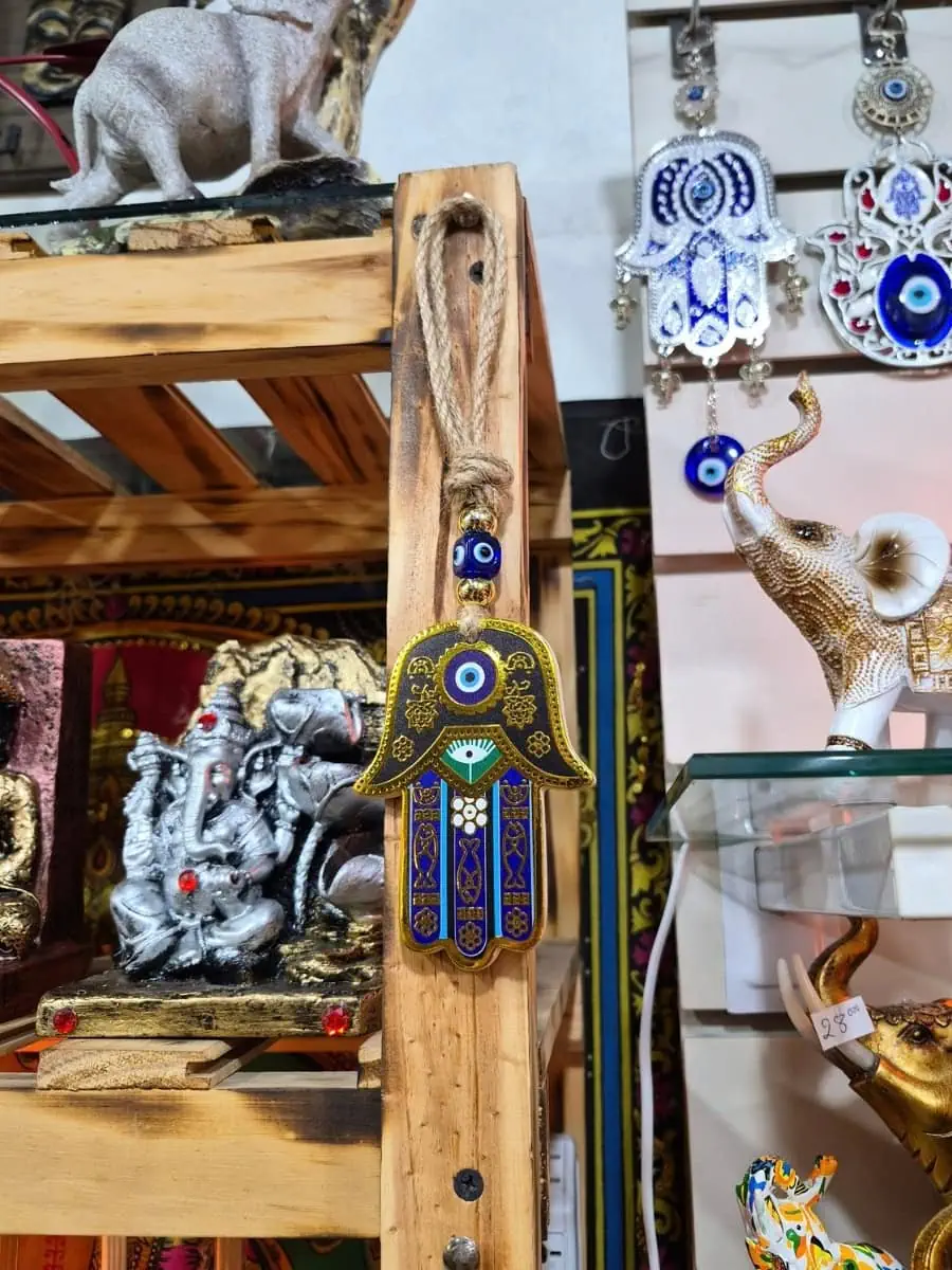 Mano de Fátima decorativa con fondo dorado, dedos azules, ojo turco central y detalles geométricos