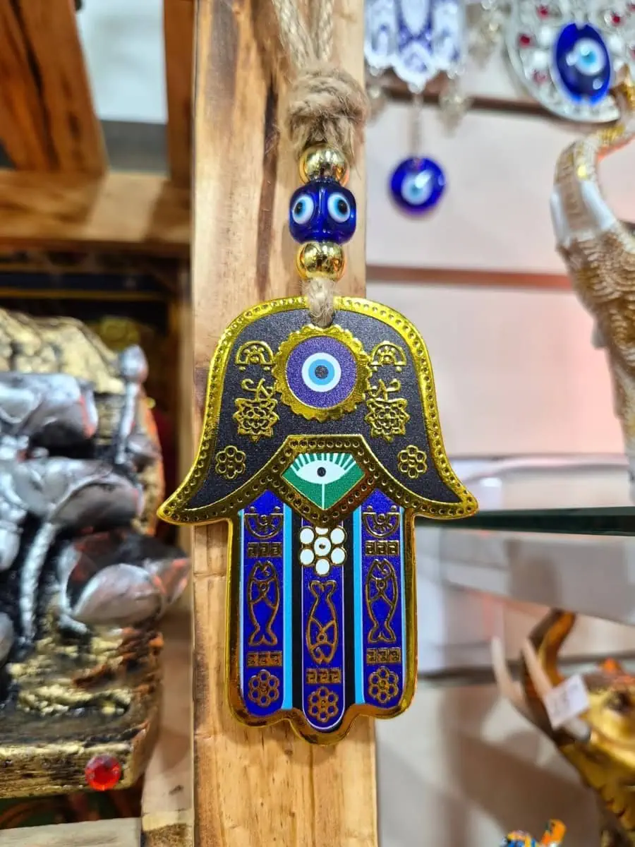 Mano de Fátima decorativa con fondo dorado, dedos azules, ojo turco central y detalles geométricos