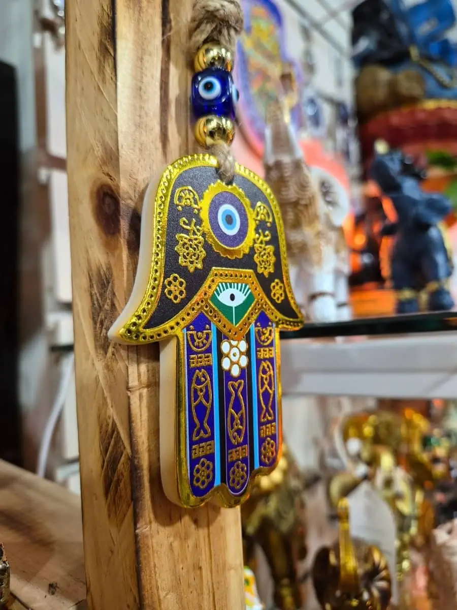 Mano de Fátima decorativa con fondo dorado, dedos azules, ojo turco central y detalles geométricos