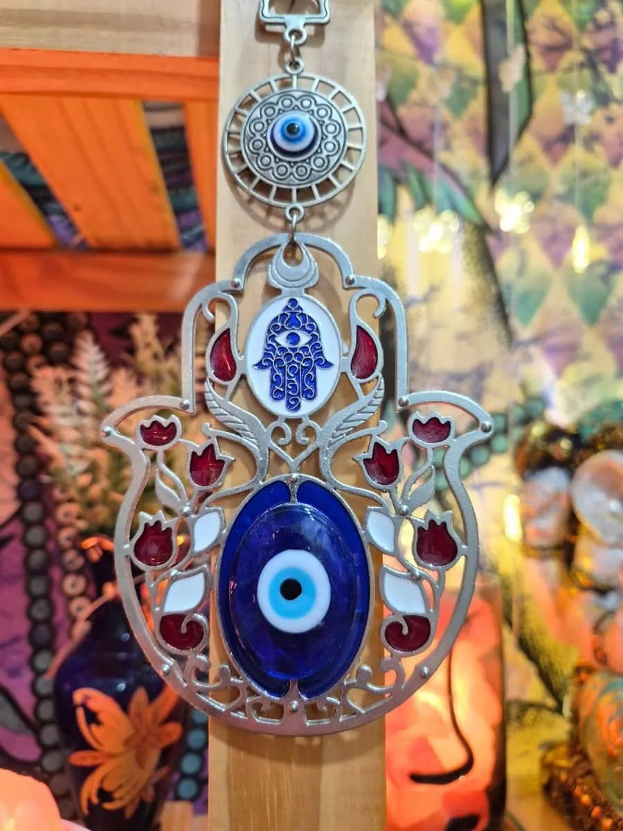 Mano de Fátima plateada calada con motivos florales rojos, pequeño símbolo Hamsa y ojo turco azul grande central
