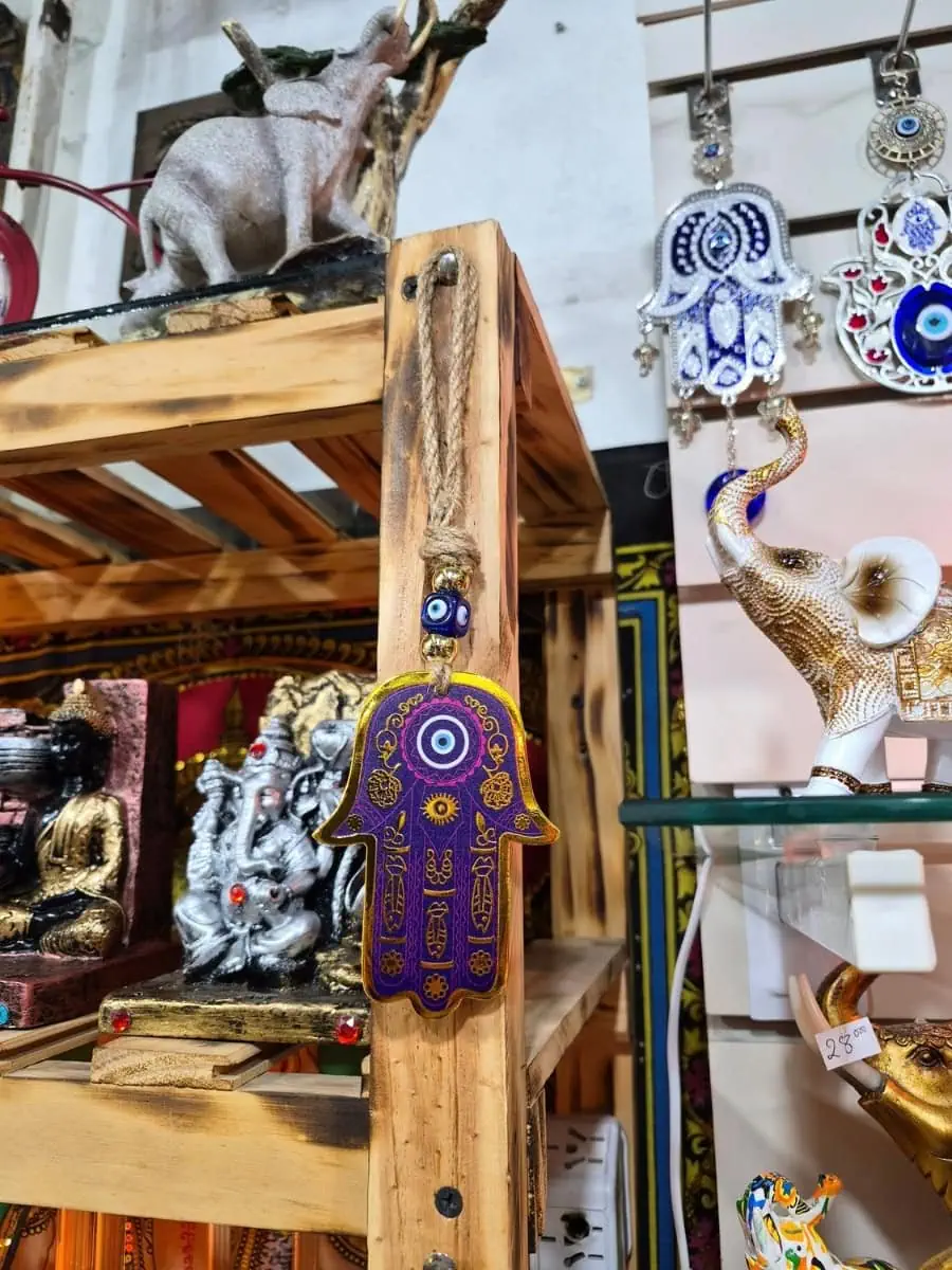 Mano de Fátima violeta con bordes dorados, ojo turco azul y dibujos ornamentales sobre cordón de soga