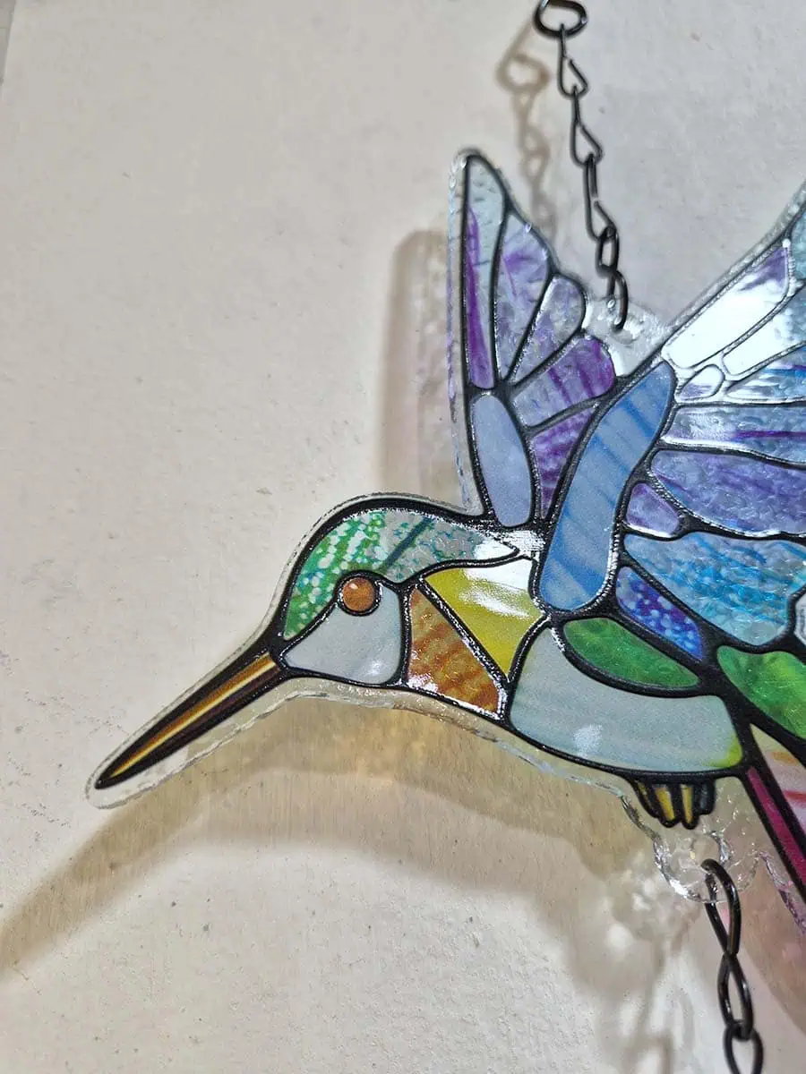 Colgante decorativo de colibrí en vitró celeste, lila, verde y rosa con campana de metal
