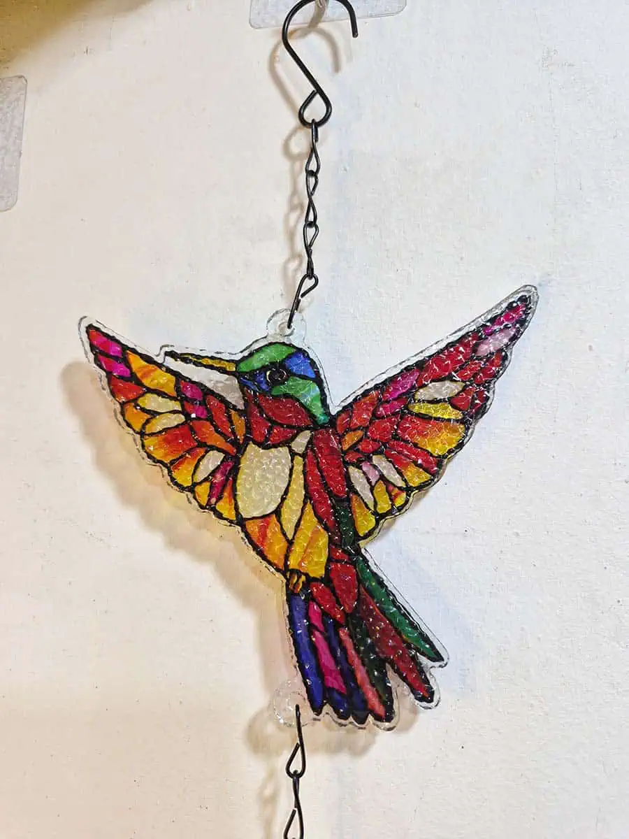 Colgante decorativo de colibrí en vitró rojo y rosa con detalles amarillos y campana de metal