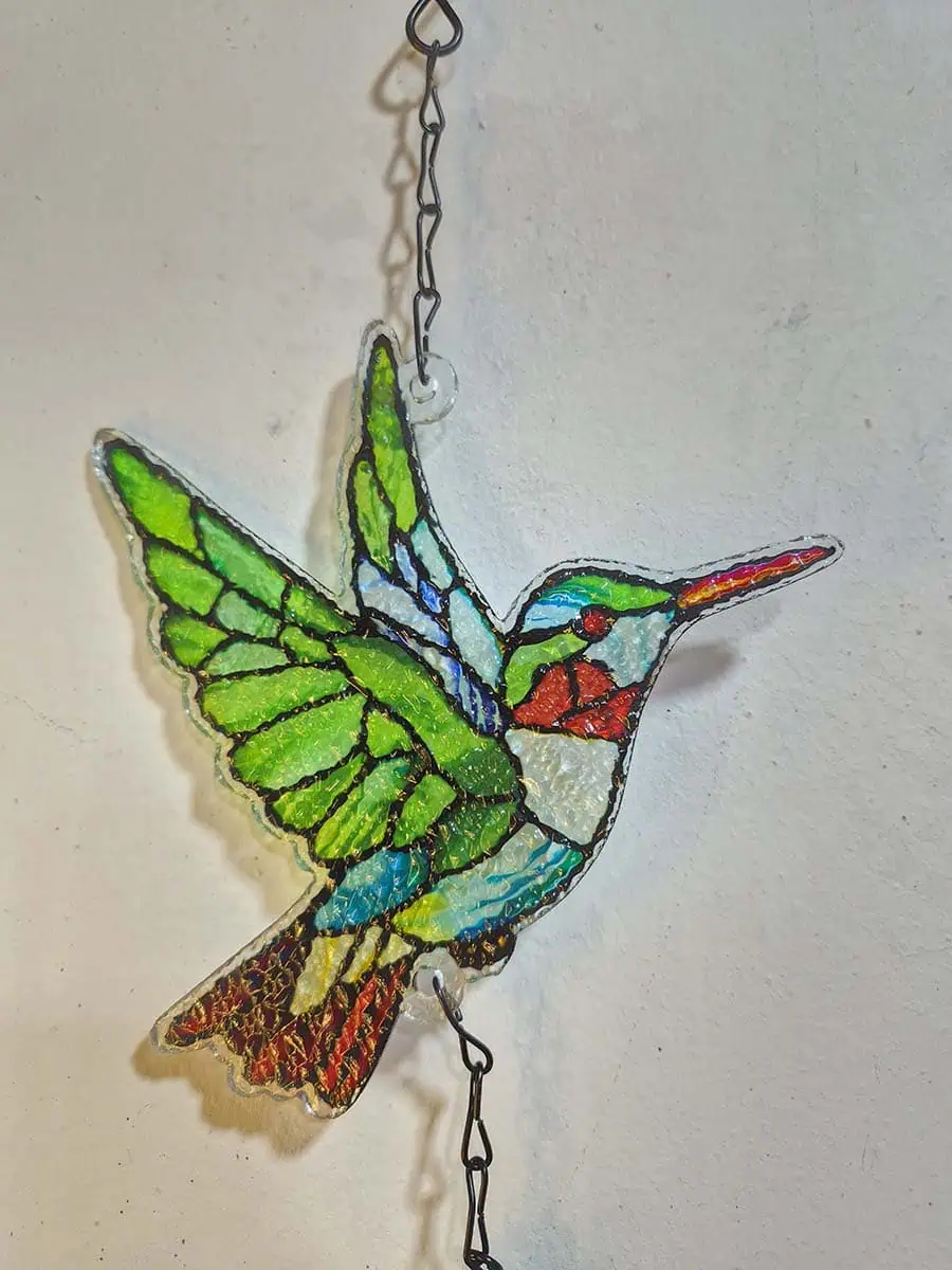 Colgante decorativo de colibrí en vitró verde con detalles rojos y campana de metal