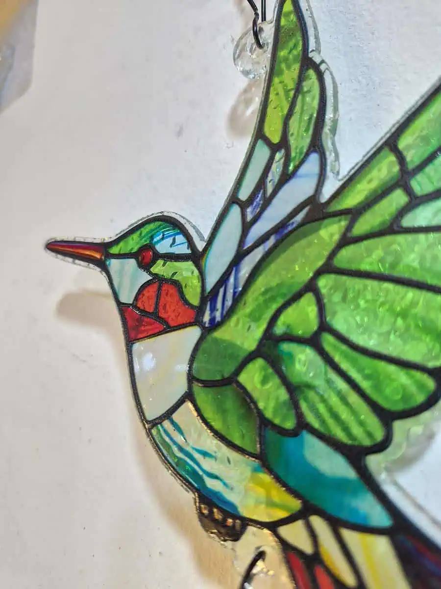 Colgante decorativo de colibrí en vitró verde con detalles rojos y campana de metal