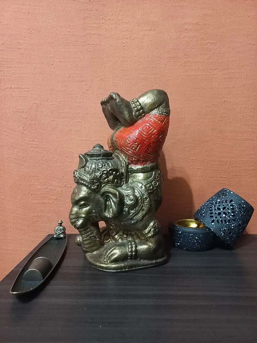 imagen de una ganesha decorativa haciendo yoga para la casa de color bronce con naranja