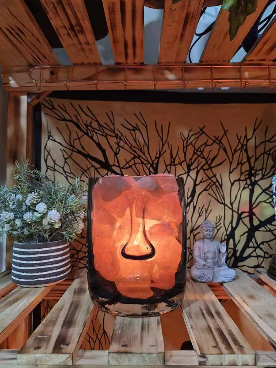 Lámpara de sal del Himalaya con piedras iluminadas dentro de un recipiente de vidrio con diseño de rostro