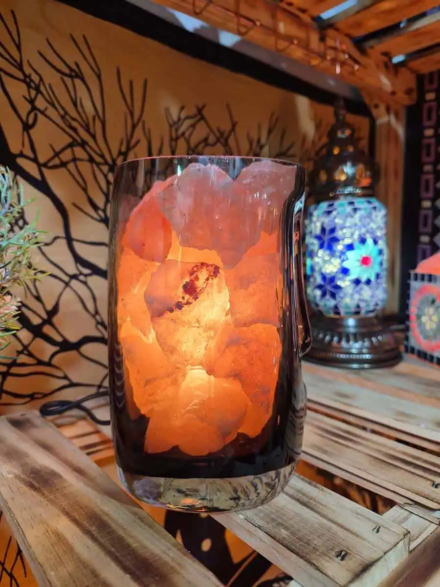 Lámpara de sal del Himalaya con piedras iluminadas dentro de un recipiente de vidrio con diseño de rostro