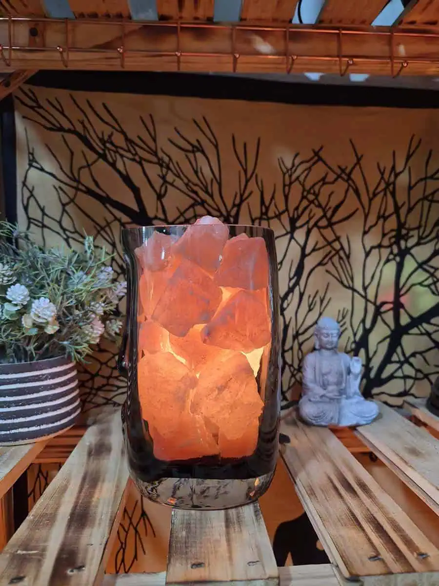 Lámpara de sal del Himalaya con piedras iluminadas dentro de un recipiente de vidrio con diseño de rostro