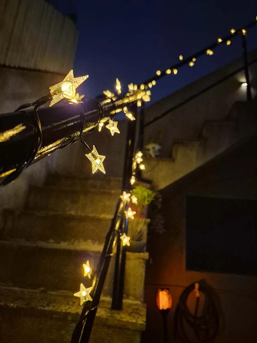 Guirnalda solar de estrellas con luz cálida de 10 metros decorando una escalera y su baranda exterior.