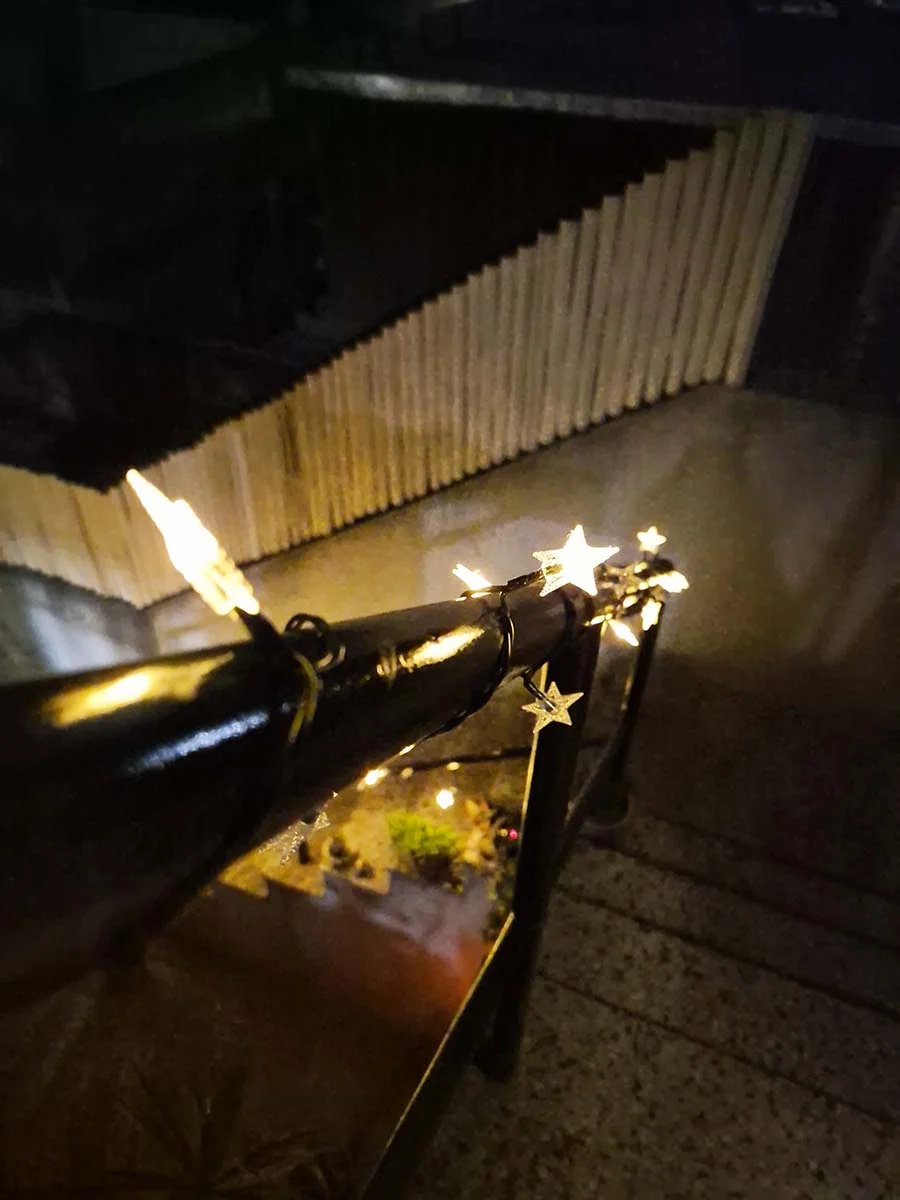 Guirnalda solar de estrellas con luz cálida de 10 metros decorando una escalera y su baranda exterior.