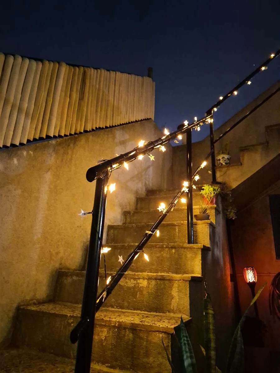 Guirnalda solar de estrellas con luz cálida de 10 metros decorando una escalera y su baranda exterior.