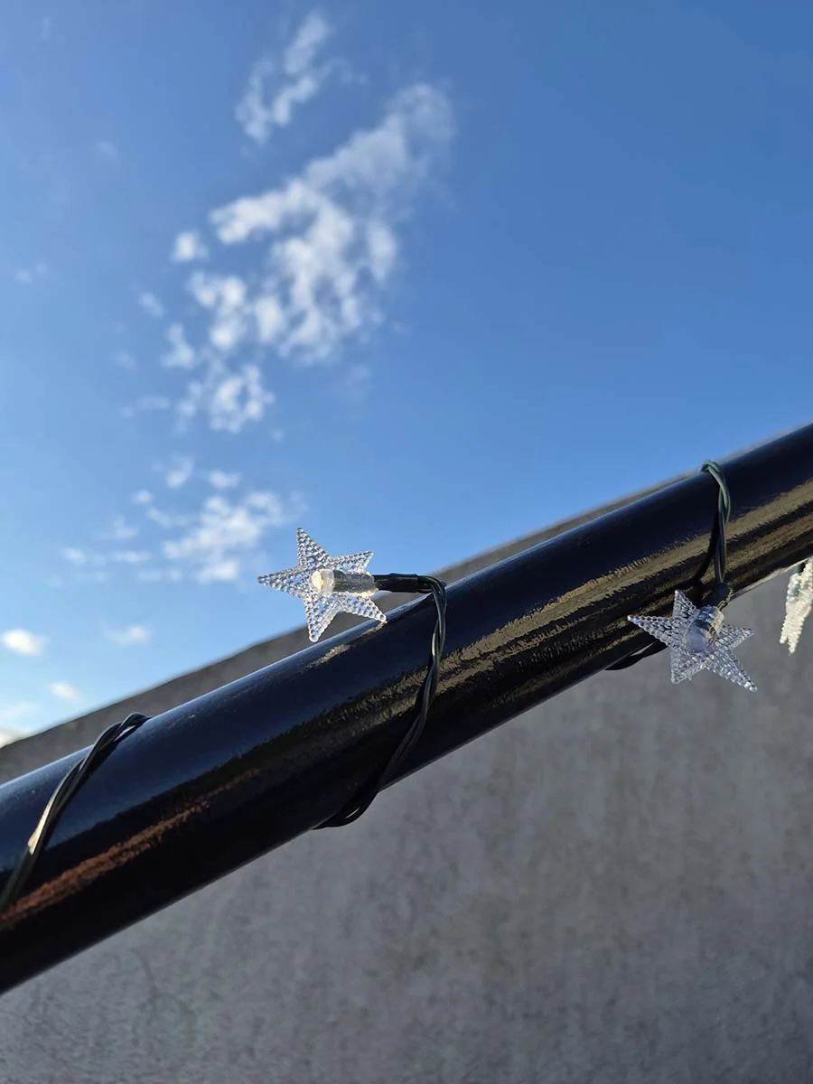 Guirnalda solar de estrellas con luz cálida de 10 metros decorando una escalera y su baranda exterior.