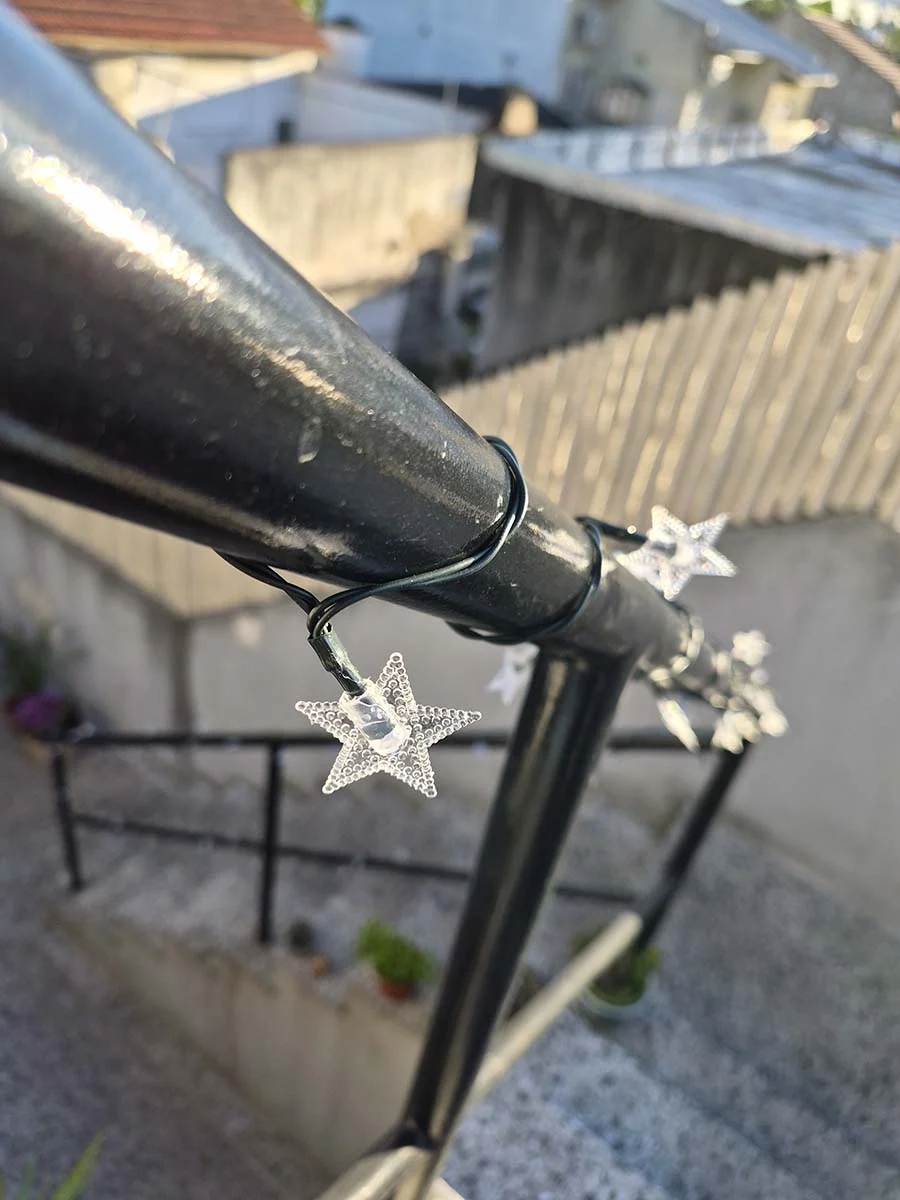 Guirnalda solar de estrellas con luz cálida de 10 metros decorando una escalera y su baranda exterior.