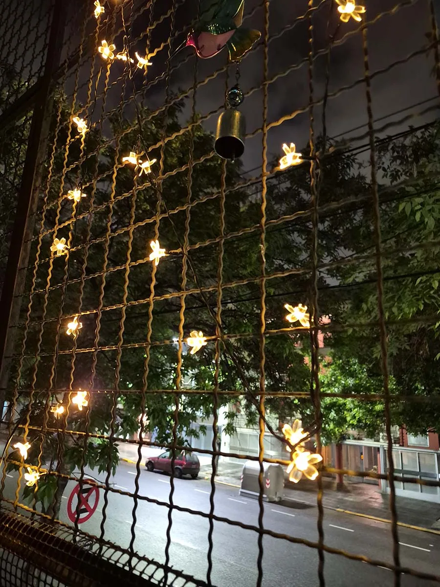 Guirnalda solar de flores con luz cálida de 10 metros decorando la reja de un balcón durante la noche.