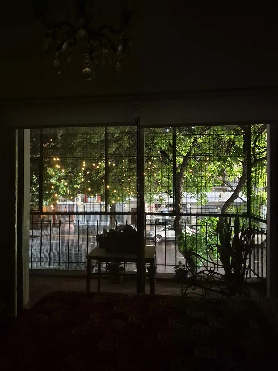 Guirnalda solar de flores con luz cálida de 10 metros decorando la reja de un balcón durante la noche.