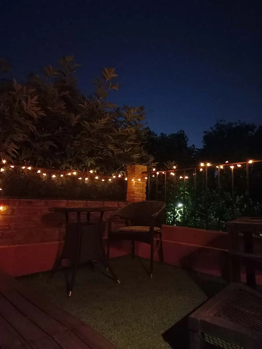 Guirnalda solar de abejitas con luz cálida decorando la baranda y pared de una terraza durante la noche.
