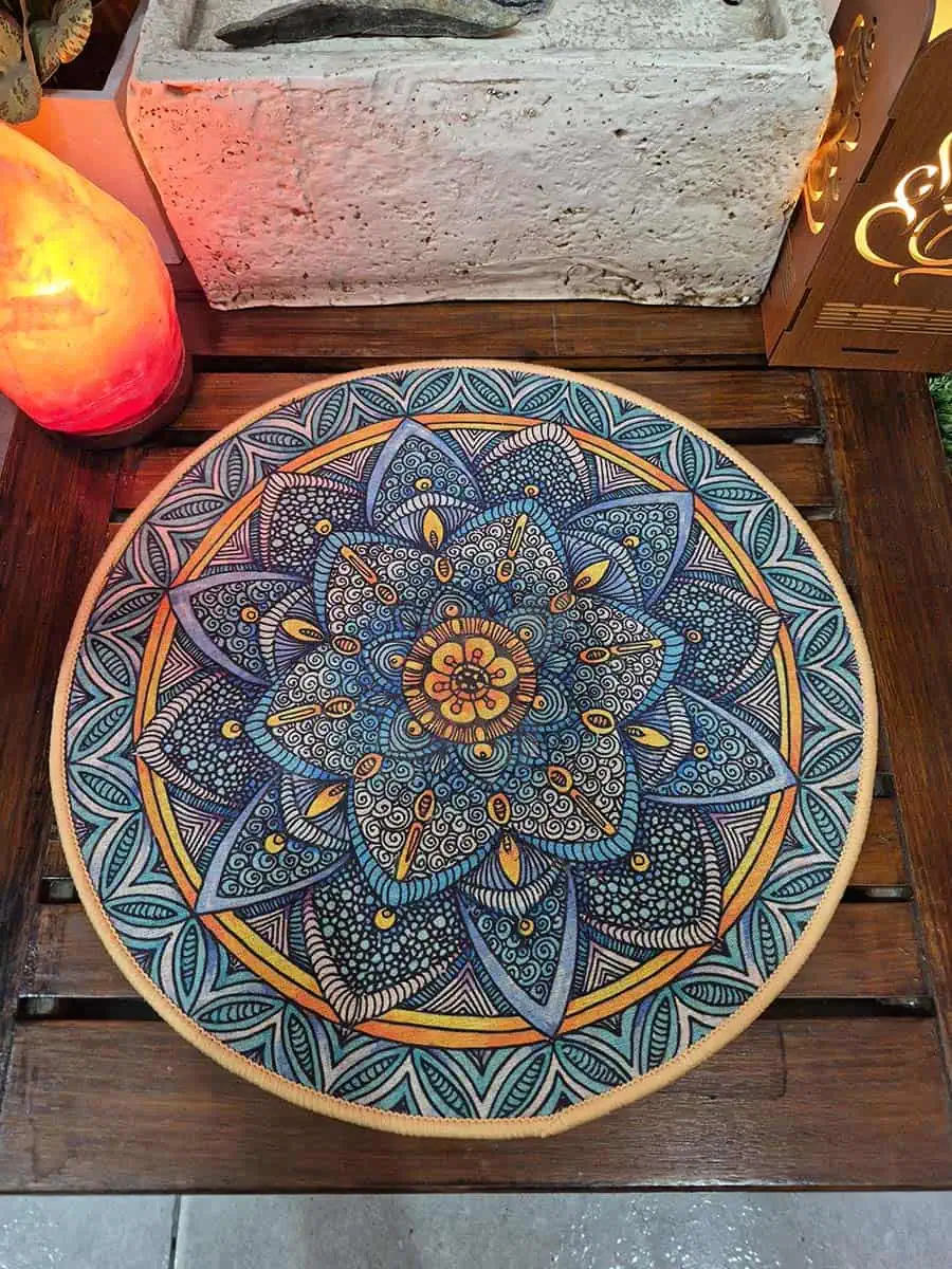 Individual redondo con mandala gris, celeste y naranja con diseño floral detallado
