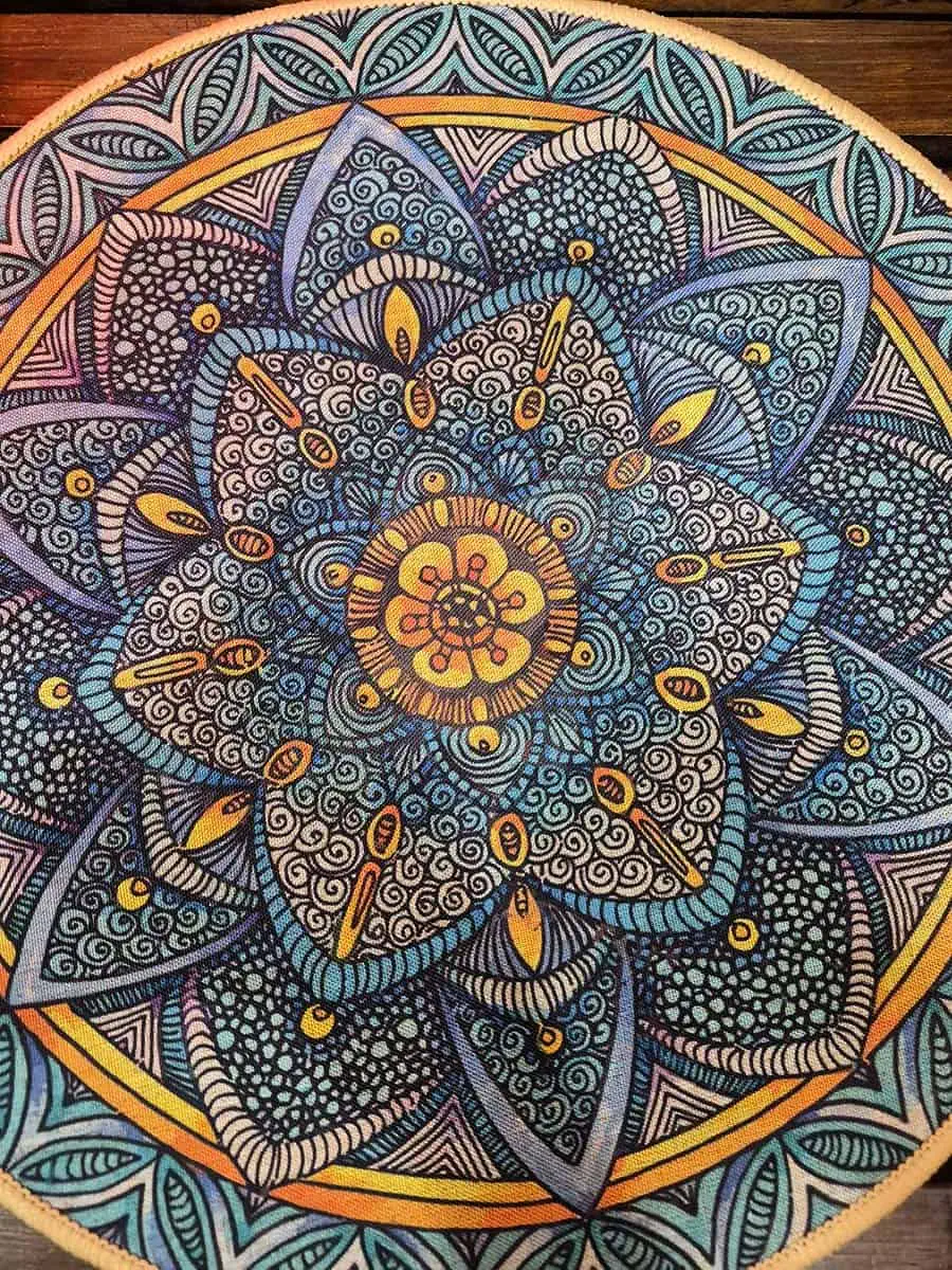 Individual redondo con mandala gris, celeste y naranja con diseño floral detallado