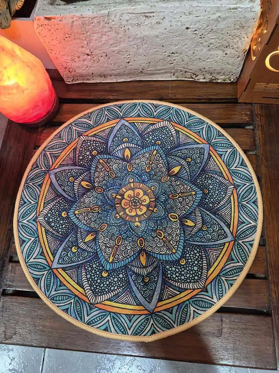 Individual redondo con mandala gris, celeste y naranja con diseño floral detallado